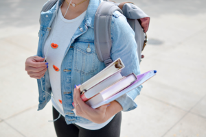 busto di bambina con in mano libri di scuola