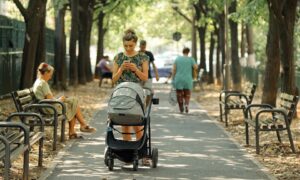 ragazza cammina in un parco con passeggino per bambino