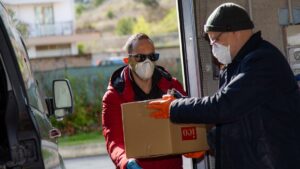 La povertà alimentare, due persone si passano un pacco alimentare