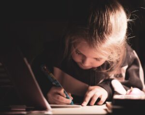 ragazza che scrive sul quaderno di scuola per fare i compiti