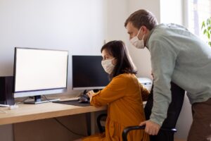 colleghi di lavoro con la mascherina che leggono un documento al computer