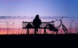 ragazza seduta in una panchina che guarda il tramonto