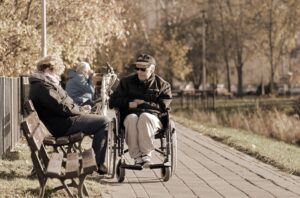 una persona anziana sulla sedia a rotella è al parco accompagnato dalla badante