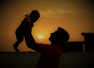 Un uomo che alza un bambino al cielo con sullo sfondo un tramonto. È l'immagine di copertina di un articolo di Secondo Welfare sul welfare aziendale bidirezionale del Consorzio Solidarietà Sociale di Forlì-Cesena