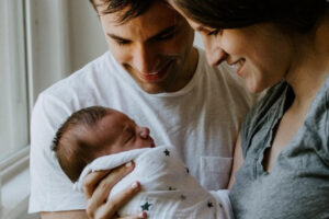 Genitori con il loro bambino neonato. Immagine di copertina di un articolo di Secondo Welfare su un articolo dell'Alleanza per l'infanzia dedicato a come affrontare le grandi sfide legate alla natalità in italia