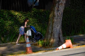 L'immagine mostra una donna che spinge un passeggino. L'immagine è la copertina dell'articolo che parla del report di WeWorld sulla situazione dei diritti di donne, bambini e bambine.
