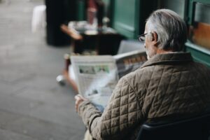 Un anziano legge un giornale. Immagine di copertina di un articolo di Secondo Welfare sulla proposta del Patto per un nuovo welfare per la non autosufficienza sulla riforma