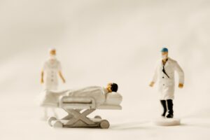 Miniature di un dottore, una infermiera e un malato. Immagine di copertina di un articolo di Secondo Welfare intitolato "Investire nel Servizio Sanitario conviene a tutti" ul rapporto Fnomceo Censis