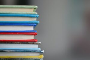 Pila di libri. Immagine di copertina dell'articolo di Secondo Welfare "Oltre i punteggi: il potenziale dei dati INVALSI che dovremmo imparare a sfruttare" per il progetto Nova Schol@