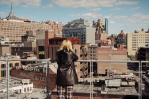 Donna che guarda la città. Immagine di copertina di un articolo di Secondo Welfare sull'adozione del “gender mainstreaming” nella pianificazione urbana per un accesso equo ai servizi.