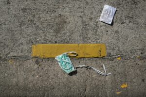 mascherina chirurgica per terra. Immagine di copertina di un articolo di Secondo Welfare sugli gli impatti sociali che la pandemia ha avuto su persone e comunità in sei città europee.