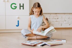 bambina che legge un libro. Immagine di copertina di un articolo di Secondo Welfare sul taglio della Legge di bilancio 2025 al Fondo per il contrasto della povertà educativa minorile.