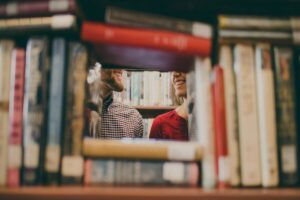 Coppia che sorride in biblioteca. Immagine di copertina di un articolo di Percorsi di secondo welfare sul ruolo della comunicazione nel coinvolgere in ambito. socio-culturale