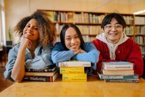tre ragazzi in biblioteca appoggiati sui libri. Foto utilizzata come immagine di copertina di un articolo di Percorsi di secondo welfare sulle esperienze italiane: Da Altamura a Napoli, passando per Firenze e Nichelino, biblioteche che hanno trovato modi innovativi per coinvolgere e includere gli adolescenti.