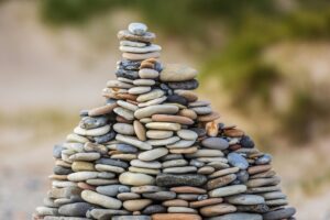 mucchio di pietre una sopra l'altra in equilibrio. Foto utilizzata come immagine di copertina di un articolo di Percorsi di secondo welfare sulle relazioni fiduciarie, capacity building e coprogettazione tra fondazioni e Terzo Settore