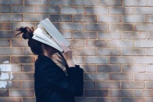 ragazza con libro in faccia. immagine di copertina di un articolo di percorsi di secondo welfare sul progetto di ricerca “PrimaGen. Laureati di prima generazione. Inclusione, supporto, valorizzazione”