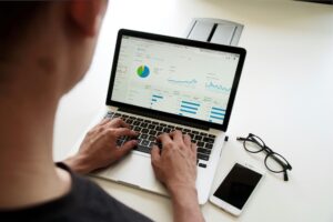 Persona che guarda grafici e dati al computer. Immagine di copertina di un articolo di Percorsi di secondo welfare sull'indagine “Benefits and Trends” di Aon Italia.