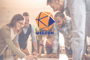 Persone che lavorano in gruppo intorno a un tavolo con il logo di Welcom - Manager del Welfare di Comunità. Immagine di copertina di un articolo di Percorsi di secondo welfare sulle cinque posture per il lavoro sociale di comunità