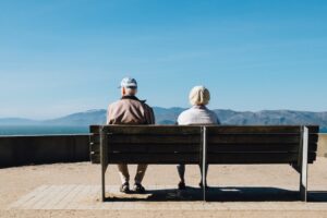 coppia di signori anziani che guarda l'orizzonte da una panchina. Immagine di copertina di un articolo di secondo welfare sulla long term care in Italia.