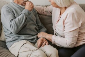 Una donna anziana aiuta il marito non autosufficiente. Immagine di copertina di un articolo in cui Percorsi di secondo welfare segnala un comunicato del Patto per un Nuovo Welfare sulla Non Autosufficienza sulla necessità di una legge nazionale che riconosca i caregier familiari