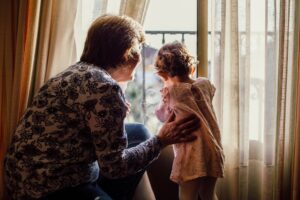 nonna e nipote che guardano fuori dalla finestra. Foto utilizzata come immagine di copertina di un articolo di Percorsi di secondo welfare sul ruolo dei nonni nella società
