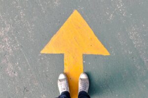 Foto di una freccia disegnata per terra. Immagine di copertina di un articolo di percorsi di secondo welfare su il welfare aziendale di FNM e Trenord