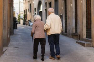 Foto di due persone anziane che camminano. Immagine di copertina di un articolo di Percorsi di secondo welfare su Reti di comunità per sostenere gli anziani fragili: l’esperienza di An.Co.Re.