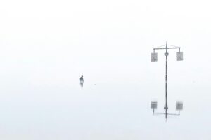 Un uomo che sembra fluttuare nel cielo insieme a una struttura metallica. Immagine di copertina dell'articolo di Percorsi di secondo welfare "Long Term Care: perché la definizione è l'infrastruttura invisibile del sistema" scritto da Carlo Conforti (Ordine degli Attuari)