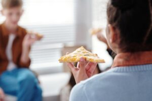 Adolescenti che mangiano la pizza. Immagine di copertina di un articolo di Percorsi di Secondo Welfare con un'intervista a Ilaria Madama sulla povertà alimentare tra gli adolescenti