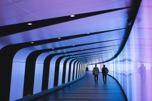 Persone in un tunnel violetto. Immagine di copertina di un articolo di Percorsi di Secondo Welfare sull'evento "Il Fattore Economia Sociale" che si svolge a Roma il 20 e 21 novembre 2025
