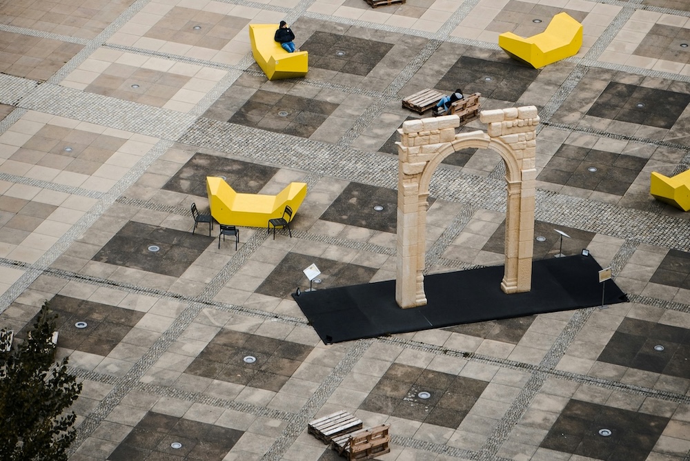 Una piazza urbana con sedute e una installazione artistica a forma di arco. Immagine di un articolo di Percorsi di Secondo Welfare sui nessi tra mobilità e politiche sociali