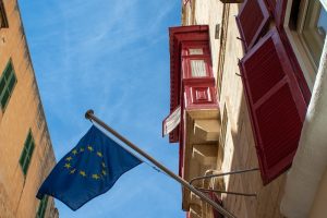 Foto di una casa con bandiera dell'UE. Immagine di copertina di un articolo di percorsi di secondo welfare su il piano UE sul diritto alla casa