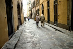 coppia di anziani che cammina per strada. immagine di copertina di un articolo di Percorsi di Secondo Welfare sulla long term care in Italia e Portogallo