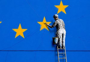Un uomo colora una stella della bandiera UE. Immagine di un articolo di Percorsi di Secondo Welfare sulla Strategia europea contro la povertà