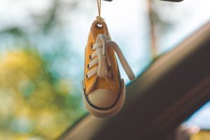 Una scarpina da neonato appesa. Immagine di copertina dell'articolo di Percorsi di Secondo Welfare "Volere non è potere: in Italia si fanno meno figli di quanti se ne desiderano"