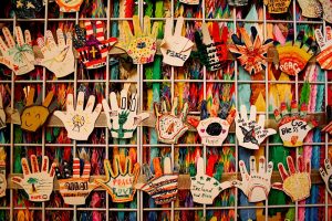Una serie di mani di carta appese a un muro che continua a crescere. Immagine di copertina di un articolo di Percorsi di Secondo Welfare sul rapporto Nonprofits and Philanthropy di Independent Sector su e fiducia nella filantropia e nel non profit negli stati uniti d'america